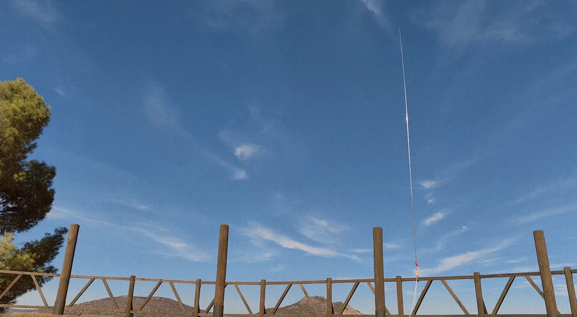 La vertical de látigo montada junto a una valla de madera, contra el cielo azul de la sierra